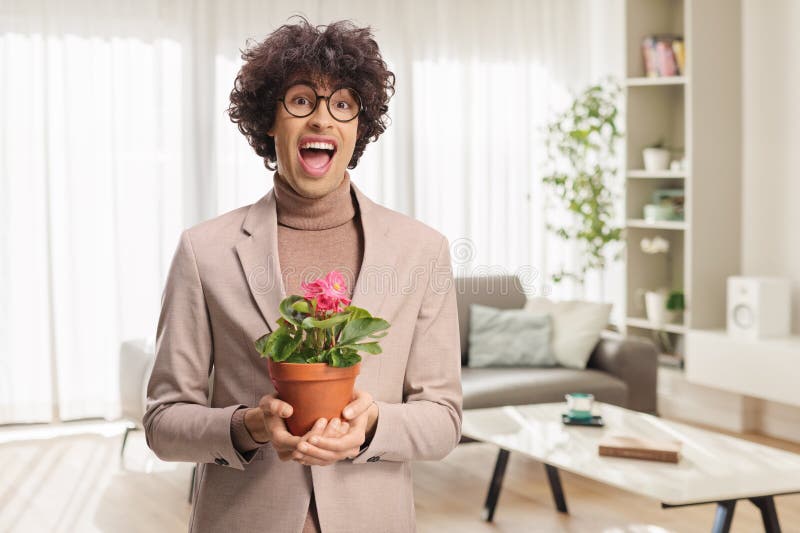 Spädd ung man som håller en blomma i en kruka arkivfoton