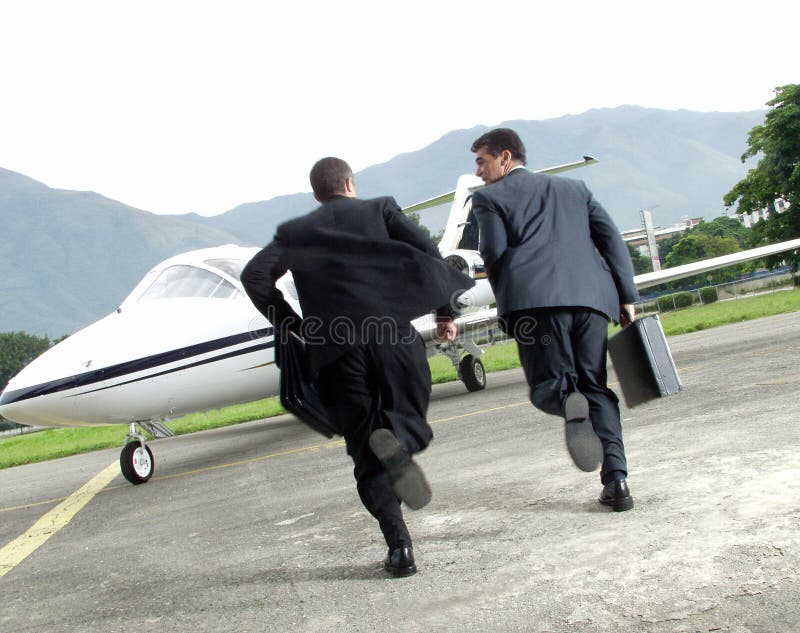 Two businessman running towards a plane. Two businessman running towards a plane.