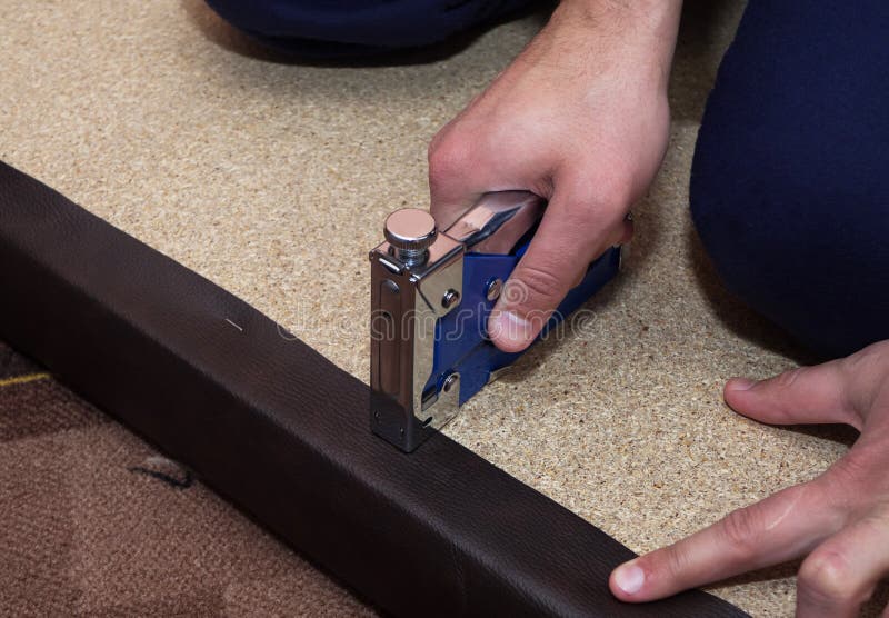 Spånskiva som stoppas med brunt läder Repairman som använder häftapparaten och häftklamrar royaltyfri fotografi Spånskiva som stoppas med brunt läder Repairman som använder häftapparaten och häftklamrar royaltyfri fotografi