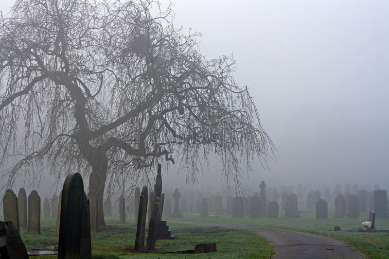 Spöklik gammal kyrkogård på en dimmig kall dag
