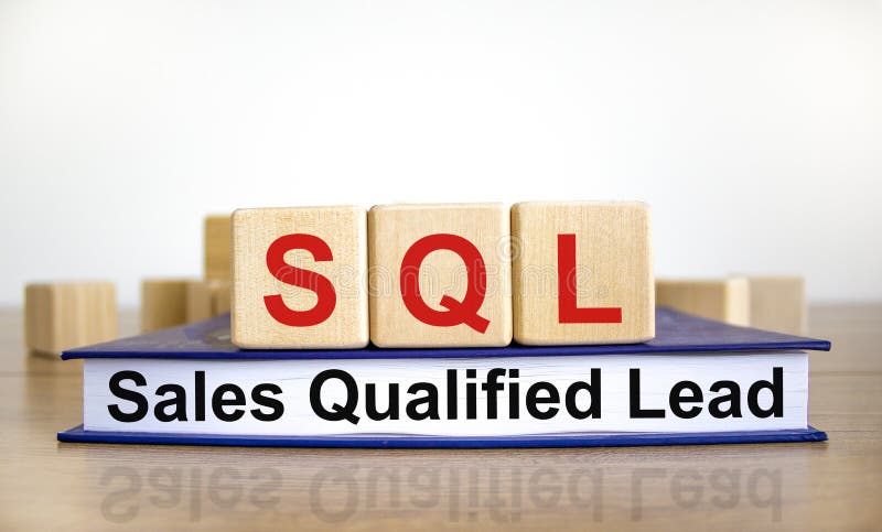 SQL sales qualified lead symbol. Wooden cubes on book with words `SQL sales qualified lead`. White background. Business and SQL stock images