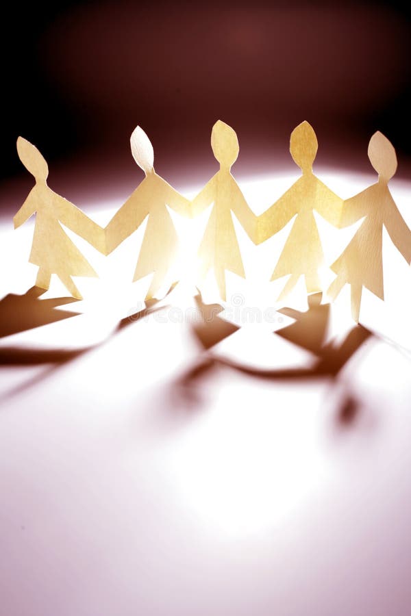 A cutout of women standing in a line holding hands made from paper, depicting a team of women. A cutout of women standing in a line holding hands made from paper, depicting a team of women.