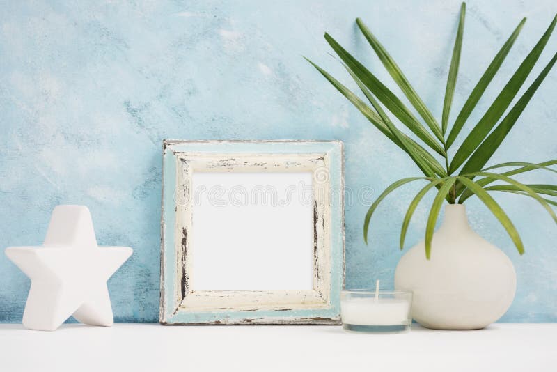 Square blue Photo frame mock up with green tropical plants in vase, ceramic star and candle on shelf. Scandinavian style royalty free stock images