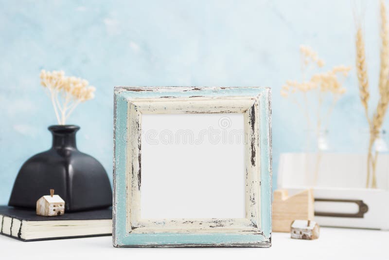 Square blue Photo frame mock up with green tropical plants in vase, ceramic star and candle on shelf. Scandinavian style