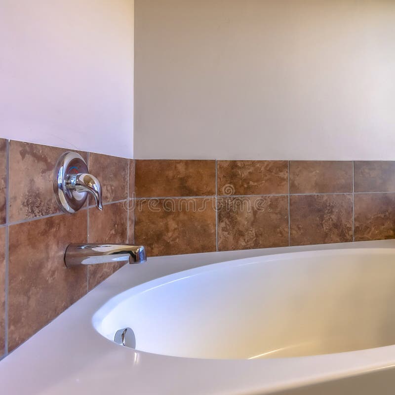 Square Close up of built in oval bathtub inside a bathroom with tiled and concrete wall royalty free stock photo