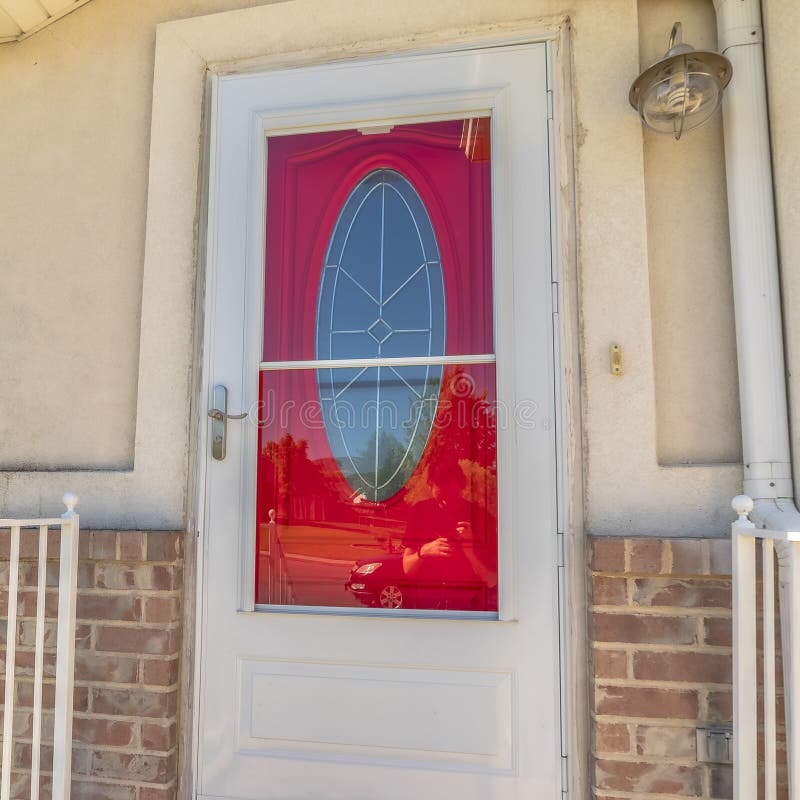 Square Exterior of a home with decorative oval glass paned vibrant red front door stock photography