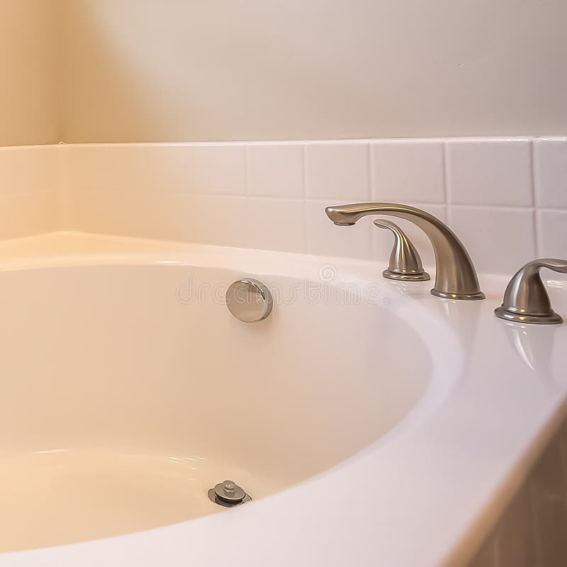Square frame Close up of a white oval bathtub with stainless steel faucet inside a bathroom royalty free stock photo
