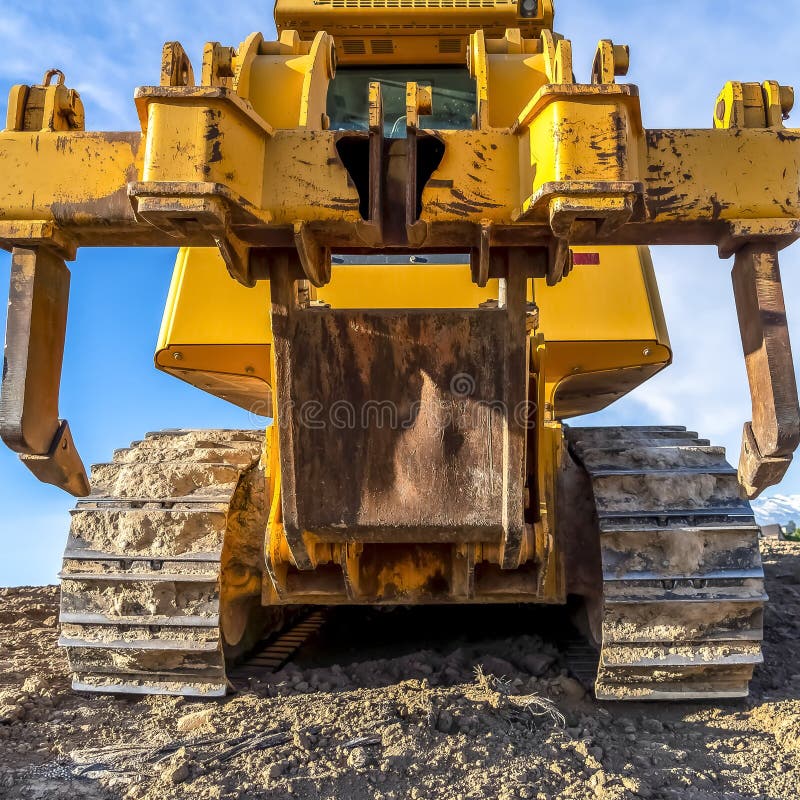 Square Heavy duty construction vehicle with peeling yellow paint and dirty metal tracks