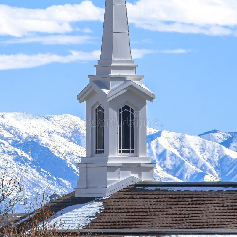 Square Rooftop of church with a modern spire design against snowy mountain and lake