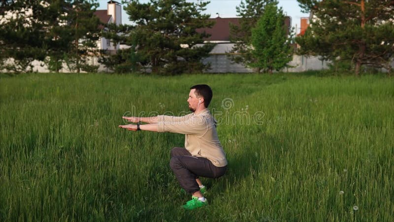 squat Человек делая сидение на корточках outdoors на открытом воздухе Он делая тренировки