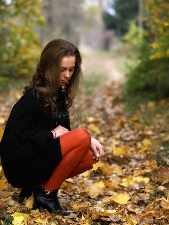 Squatting beauty girl in fall outdoor