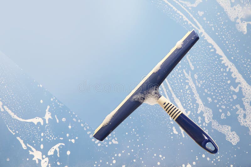Squeegee cleaning a soapy window, spring cleaning concept, blue stock images Squeegee cleaning a soapy window, spring cleaning concept, blue stock images