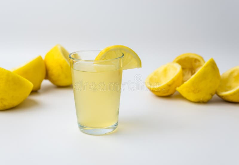 Squeezed lemon peels after making a fresh juice with glass cup on white background