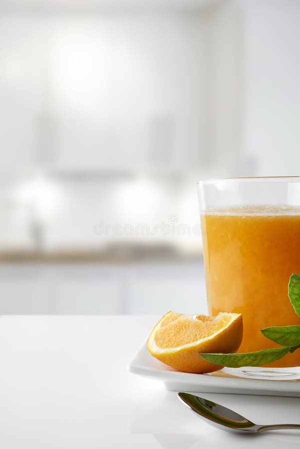 Squeezed orange juice in a glass on plate in kitchen