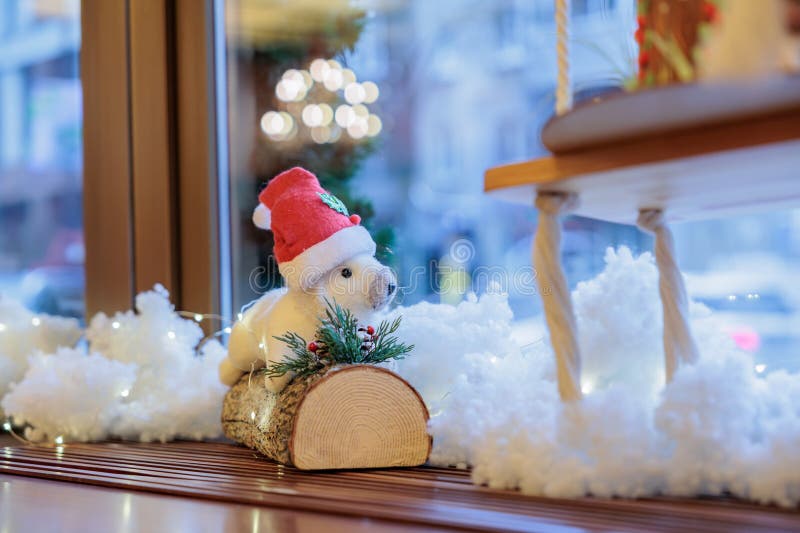 A squirrel sits on a log on a windowsill against the background of a window. Christmas decor stock images