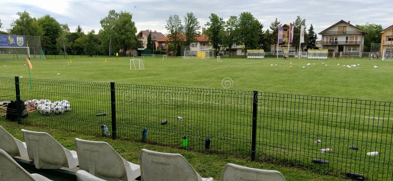 Sremska Mitrovica, Serbia May 22, 2020. School football field. Green grass behind a wire mesh fence. Free spectator seats.