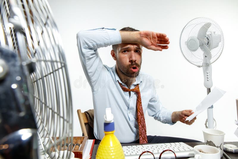 ssuffering从热的年轻人在办公室 免版税库存照片 ssuffering从热的年轻人在办公室 免版税库存照片
