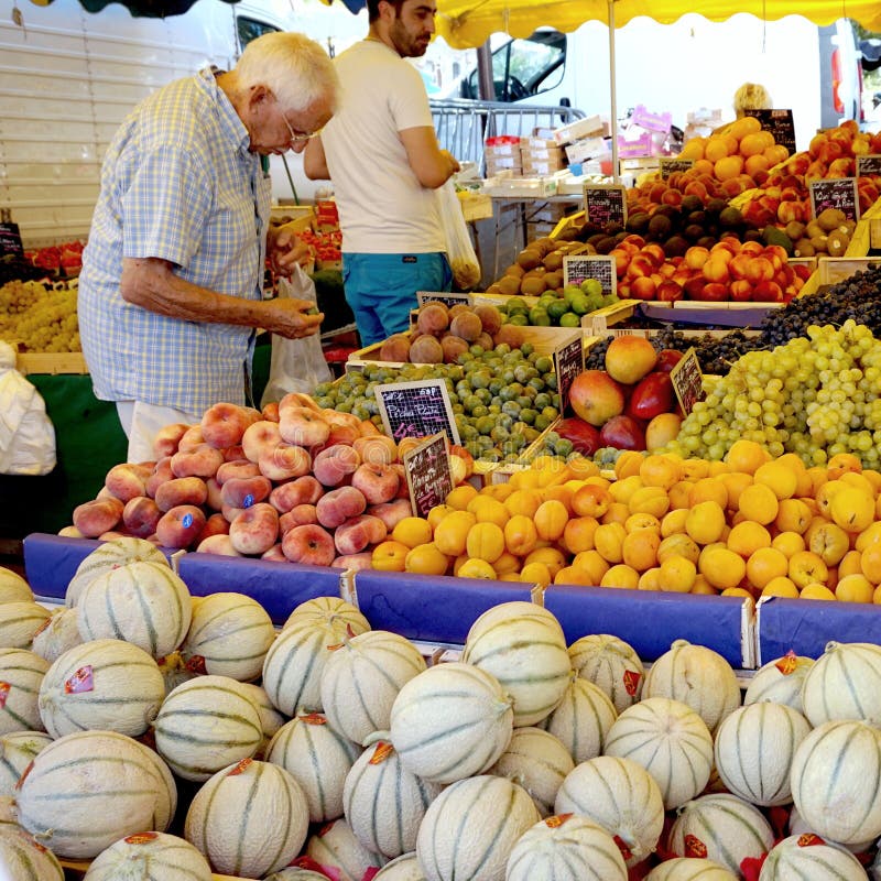 St AYGULF, VAR, PROVENCE, FRANKRIKE, AUGUSTI 26 2016: En kund som kontrollerar kiwin, persikor, druvor, melon och annan frukt på royaltyfria foton St AYGULF, VAR, PROVENCE, FRANKRIKE, AUGUSTI 26 2016: En kund som kontrollerar kiwin, persikor, druvor, melon och annan frukt på royaltyfria foton