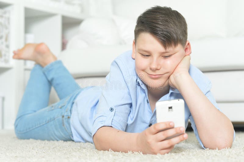 St? ende av den unga pojken med smartphonen som hemma spelar leken royaltyfria foton