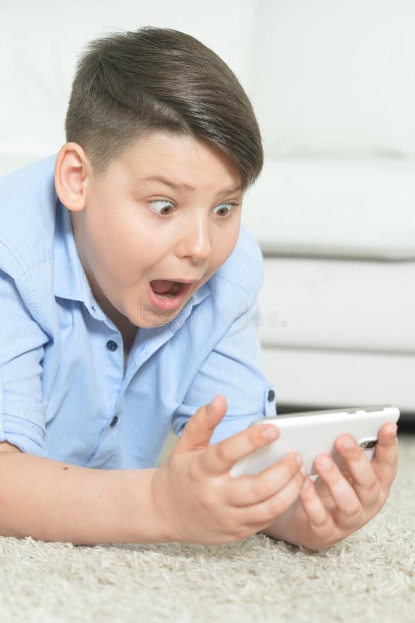 St? ende av den unga pojken med smartphonen som hemma spelar leken arkivbilder