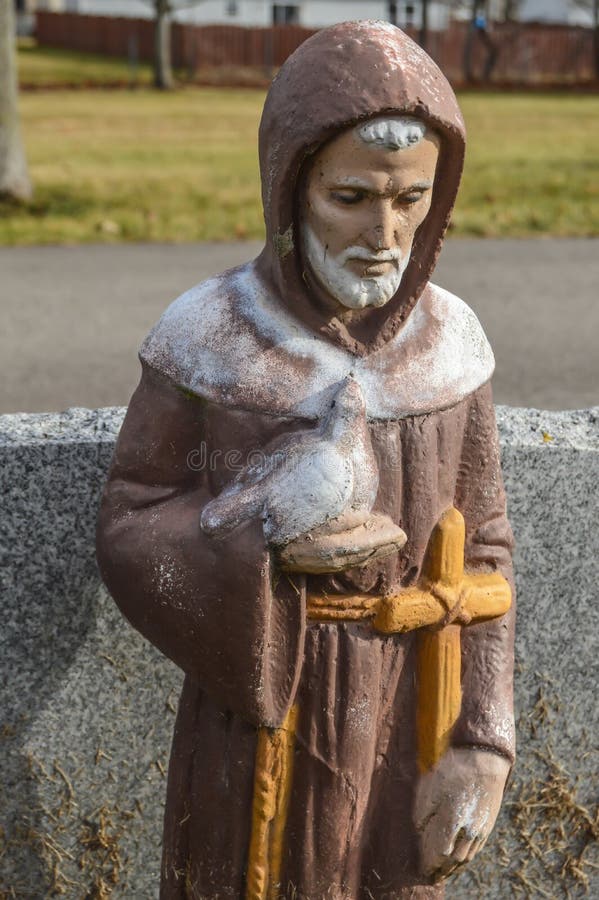 St Francis da estátua de Assisi que guarda uma pomba e uma cruz