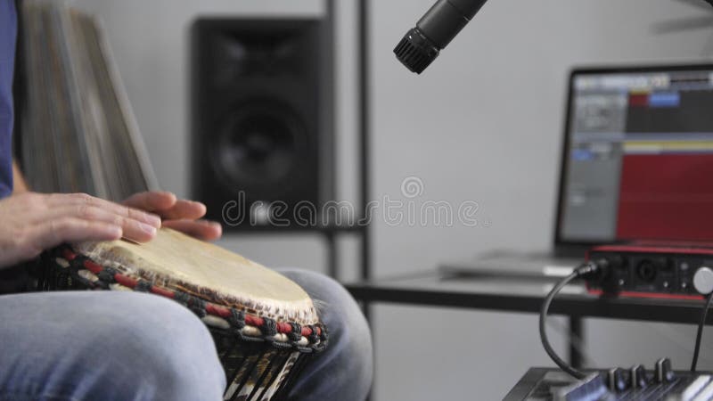 St?ng sig upp av musikern som spelar djembe f?r att trumma instrumentet i hem- musikstudio