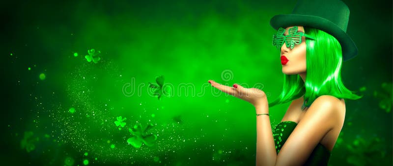 St. Patrick`s Day leprechaun laughing model girl pointing hand, holding product on green magic background decorated with shamrock leaves. Patrick Day pub party, celebrating. Ads. Art design