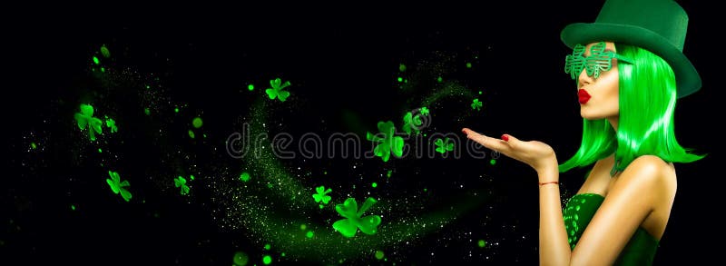 St. Patrick`s Day leprechaun model girl pointing hand, holding product, isolated on black magic background, blowing shamrock leaves. Patrick Day pub party, celebrating. Border, Widescreen