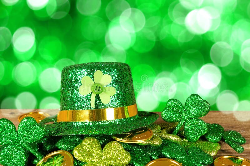 St Patricks Day leprechaun hat on a pile of gold coins and shamrocks with twinkling green background