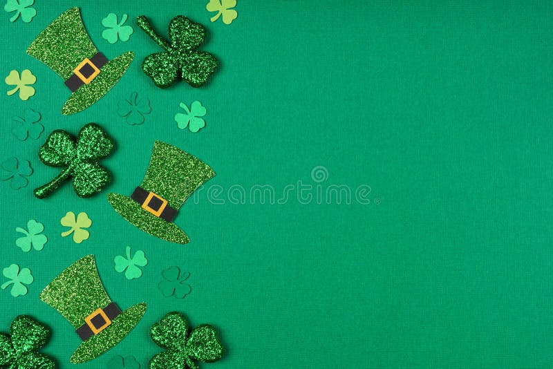 St Patricks Day shamrock and leprechaun hat side border. Top down view over a green paper background with copy space. St Patricks Day shamrock and leprechaun hat side border. Top down view over a green paper background with copy space