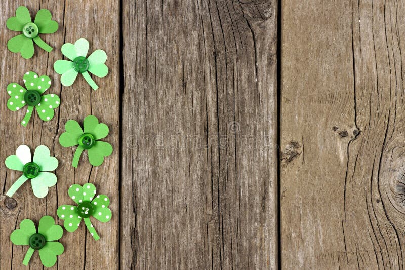 St Patricks Day side border of handmade paper shamrocks over a rustic wood background. St Patricks Day side border of handmade paper shamrocks over a rustic wood background