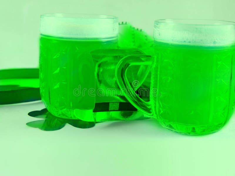 St. patricks dzień dwa szklane kubki piwa stojące na zielonym tle obok są płatki koniczyny i kapelusz. zbliżenie zdjęcie royalty free