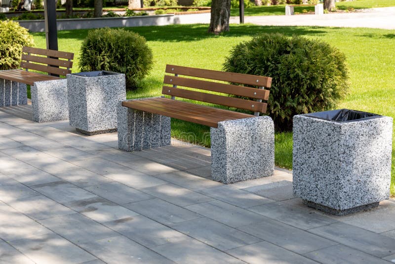 Stable wooden benches on granite bases in the park on a sunny spring day.