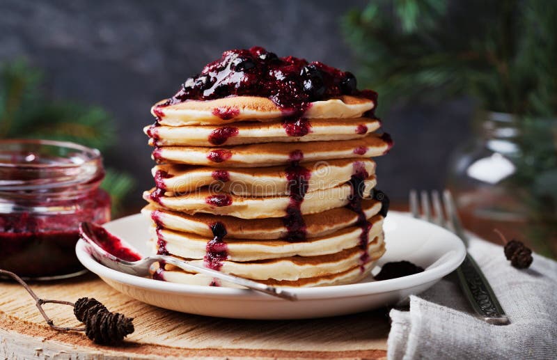 Stack of american pancakes or fritters with strawberry and blueberry jam in white plate on wooden rustic table decorated Christmas royalty free stock images Stack of american pancakes or fritters with strawberry and blueberry jam in white plate on wooden rustic table decorated Christmas royalty free stock images