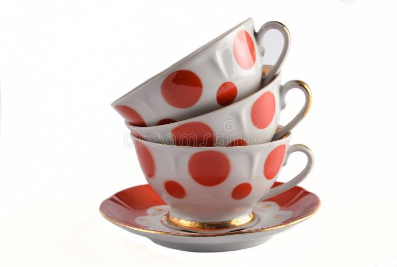 A stack of antique ceramic cups on a saucer isolated on a white background.