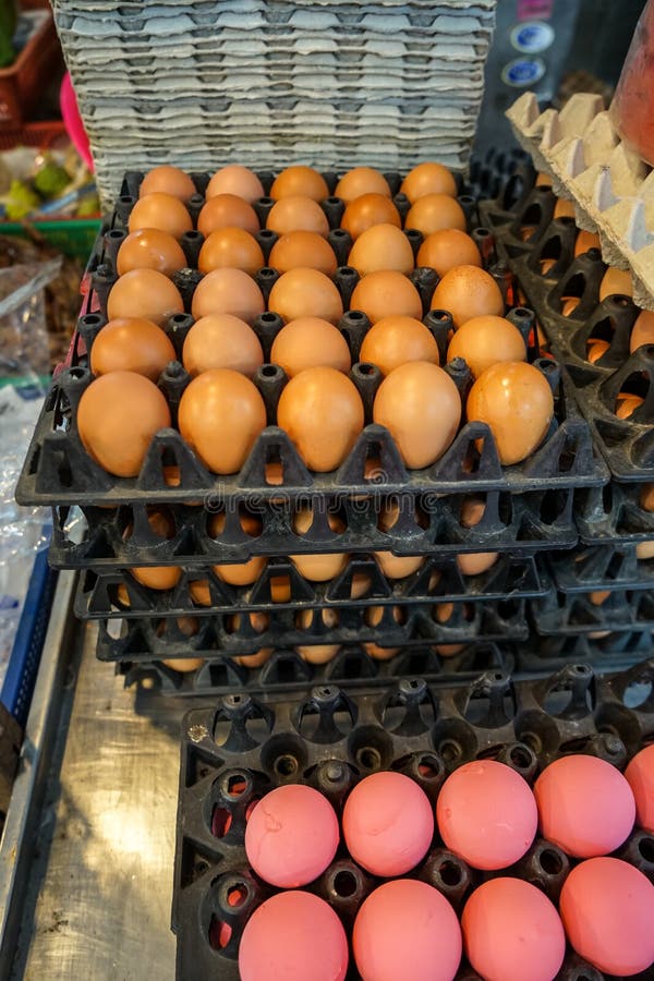 Stack of black trays full of natural light brown chicken eggs and pink preserved eggs selling in local food market royalty free stock photos Stack of black trays full of natural light brown chicken eggs and pink preserved eggs selling in local food market royalty free stock photos