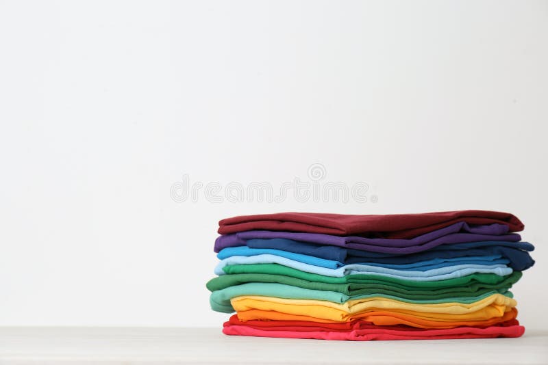 Stack of bright folded clothes on table against white background royalty free stock photos Stack of bright folded clothes on table against white background royalty free stock photos