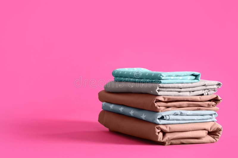 Stack of Clean Bed Sheets on Pink Background. Space for Text Stock ...