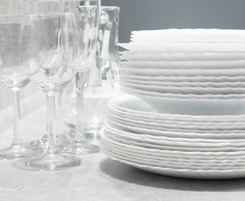 Stack of Clean Plates with Forks, Knives and Glasses for Serving Stock