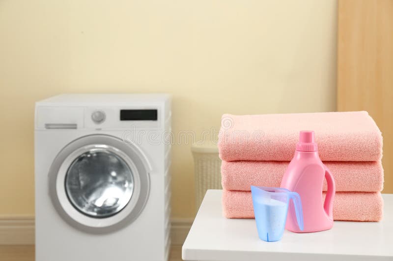 Stack of Clean Towels and Detergents on Table in Laundry Room Stock