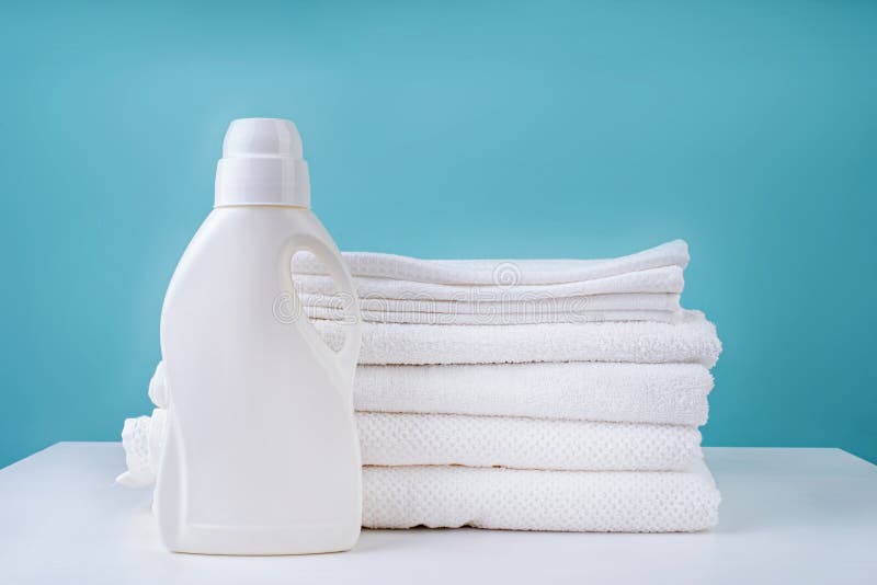 Stack of Clean Towels in a White Laundry Basket on Blue Background