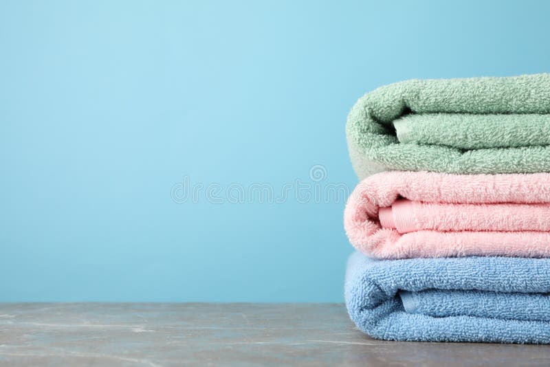 Stack of color towels on grey table against blue background