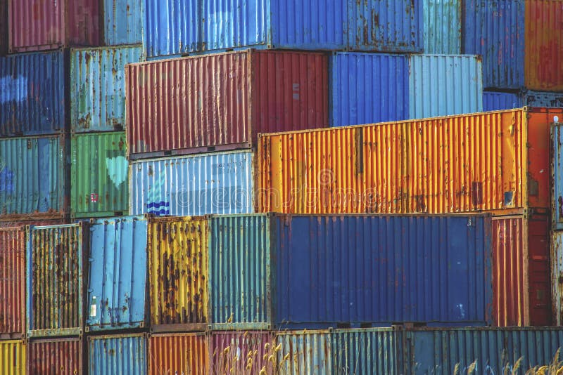 Stack of colorful old rusty sea freight containers in a port area