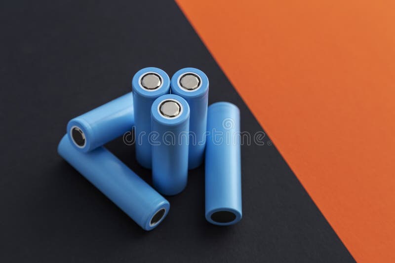Stack of 18650 cylindrical batteries on black-orange background royalty free stock photography
