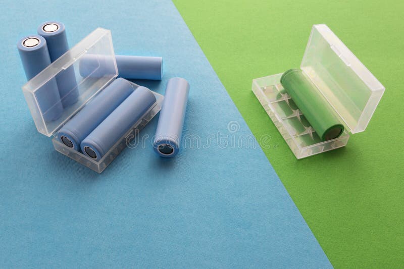 A stack of cylindrical 18650 batteries on a blue-green background royalty free stock image