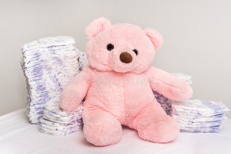 Stack of diapers or nappies with pink teddy bear