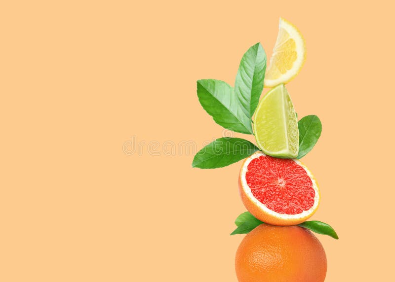 Stack of Different Fresh Citrus Fruits with Green Leaves on Pale Orange