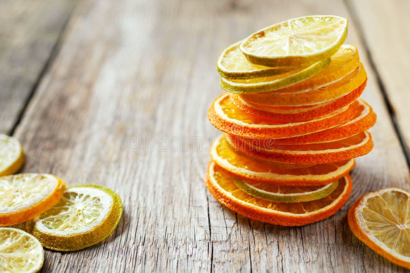 Stack of dried orange and lemon slices on wooden table.