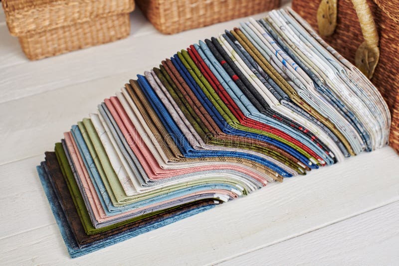 Stack of fat quarters of colorful quilting fabrics on the background of baskets royalty free stock photo