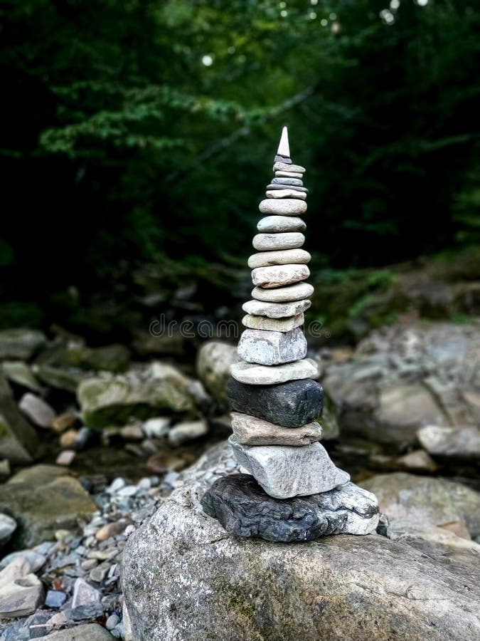 Stack of flat stones balanced by the river shore stock image